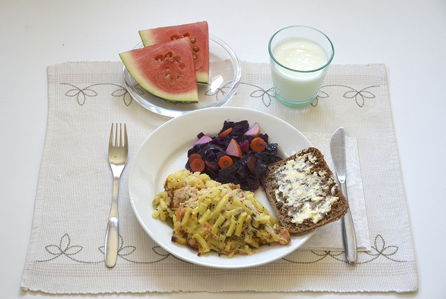 Kuvassa kirjolohilaatikko, haudutettu punakaali, ruisleipää ja levitettä, maito/piimä, vesimelonilohkot