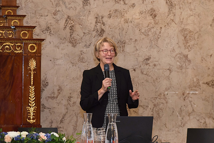 Leena Pietilä standing with microphone and talking. 