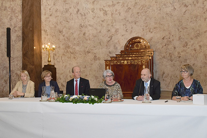 Omkring bordet sitter deltagare av paneldiskussionen. 